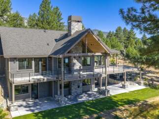 Experience luxury mountain living in this stunning custom-built home, featuring a striking stone chimney and expansive wrap-around deck perfect for enjoying the breathtaking natural surroundings.