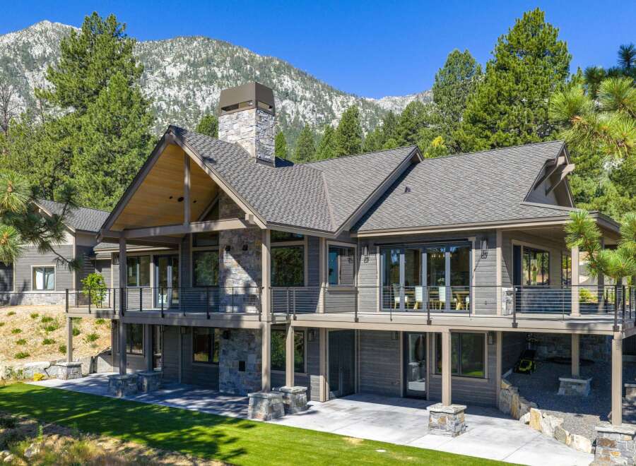 Experience luxury mountain living in this stunning home, featuring expansive decks with breathtaking views and a grand stone fireplace.