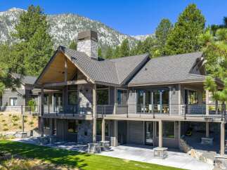 Experience luxury mountain living in this stunning home, featuring expansive decks with breathtaking views and a grand stone fireplace.