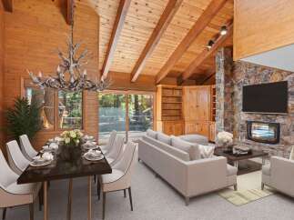 Experience rustic charm in this stunning living and dining area, featuring a grand antler chandelier and a magnificent stone fireplace.