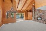 Experience rustic charm in this spacious living area featuring a stunning antler chandelier and a grand stone fireplace.