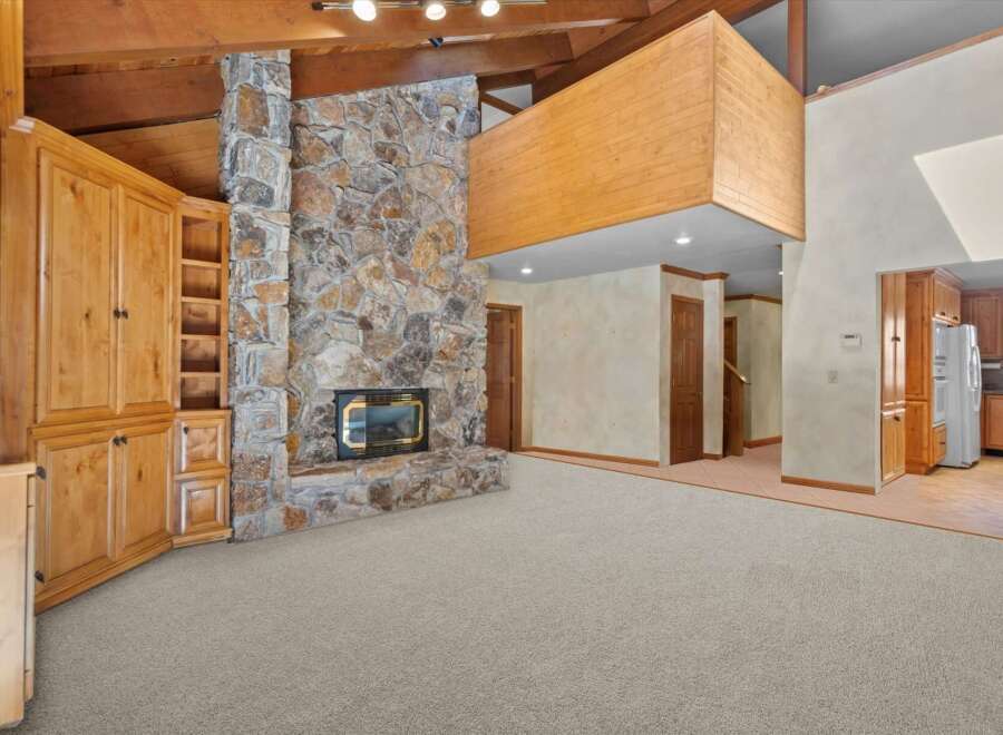 Experience rustic charm in this spacious living area featuring a grand stone fireplace as the centerpiece.