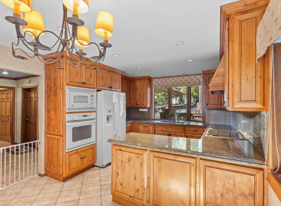 This spacious kitchen boasts beautiful natural wood cabinetry and granite countertops, offering a warm and inviting atmosphere.