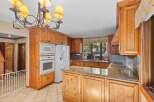 This spacious kitchen boasts beautiful natural wood cabinetry and granite countertops, offering a warm and inviting atmosphere.