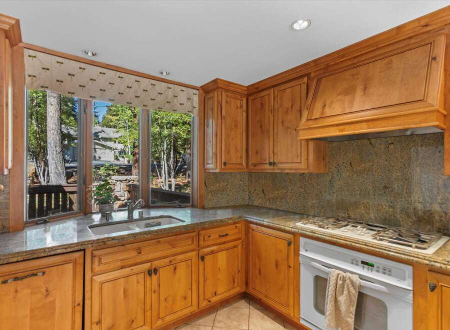 This charming kitchen features beautiful natural wood cabinetry and granite countertops, offering a warm and inviting atmosphere.