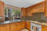 This charming kitchen features beautiful natural wood cabinetry and granite countertops, offering a warm and inviting atmosphere.