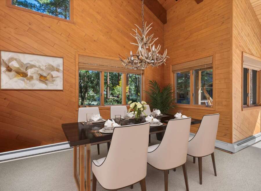 Experience rustic charm in this inviting dining room, featuring warm wood paneling and a unique antler chandelier.