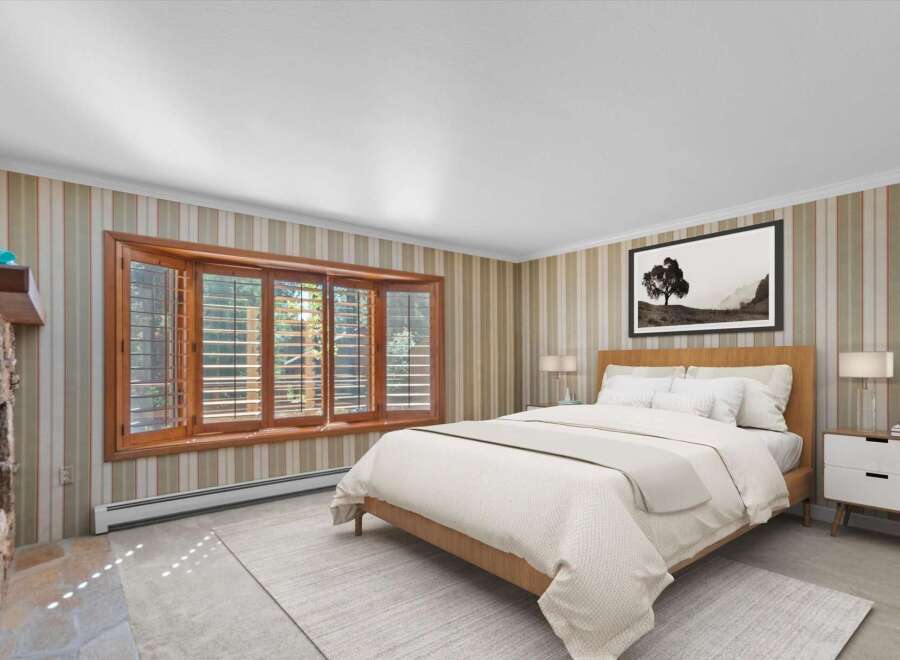 Experience comfort and style in this inviting bedroom, featuring a cozy fireplace and a large bay window that floods the space with natural light.