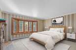 Experience comfort and style in this inviting bedroom, featuring a cozy fireplace and a large bay window that floods the space with natural light.