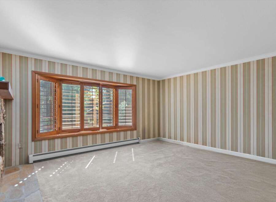Step into this inviting living space featuring a charming stone fireplace and a large bay window that floods the room with natural light.