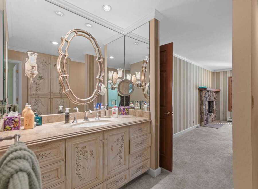 This elegant bathroom features a spacious vanity with a marble countertop and ornate cabinetry, complemented by a large, decorative mirror.