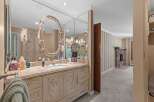 This elegant bathroom features a spacious vanity with a marble countertop and ornate cabinetry, complemented by a large, decorative mirror.