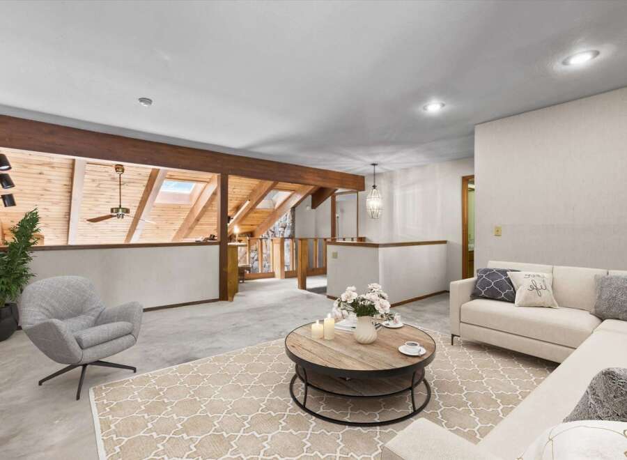 Experience the unique charm of this loft-style living space, featuring exposed wooden beams and a vaulted ceiling with skylights that flood the area with natural light.