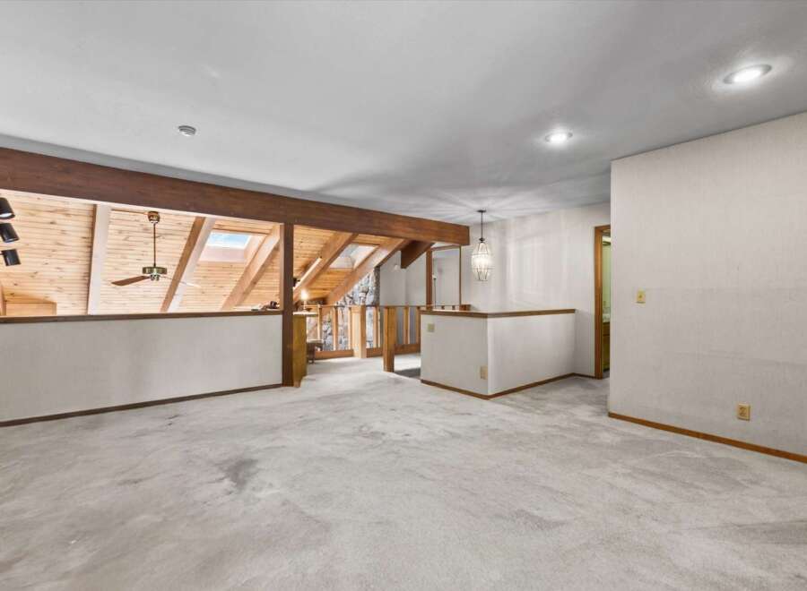 Discover this spacious loft area featuring a vaulted wood-beamed ceiling with skylights, creating a bright and airy atmosphere.