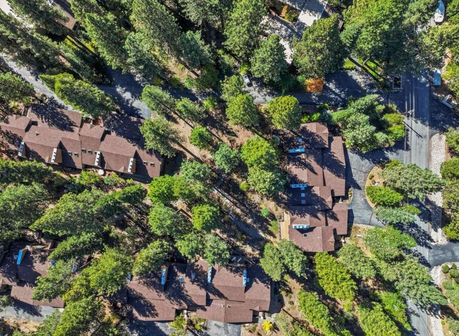 Discover this stunning aerial view of a residential complex nestled amongst lush green trees.