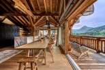 Experience luxurious mountain living in this stunning chalet, featuring a spacious open-plan dining and kitchen area with a marble island and a large wooden dining table.