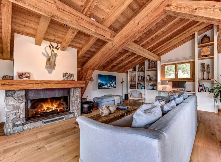 Experience rustic luxury in this stunning living room, featuring a grand stone fireplace and exposed wooden beams that create a warm, inviting atmosphere.