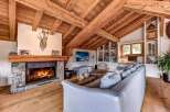 Experience rustic luxury in this stunning living room, featuring a grand stone fireplace and exposed wooden beams that create a warm, inviting atmosphere.