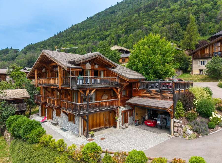 Experience luxury mountain living in this stunning multi-story chalet, featuring expansive wooden balconies and a stone-clad lower level.