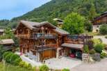 Experience luxury mountain living in this stunning multi-story chalet, featuring expansive wooden balconies and a stone-clad lower level.