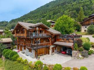 Experience luxury mountain living in this stunning multi-story chalet, featuring expansive wooden balconies and a stone-clad lower level.