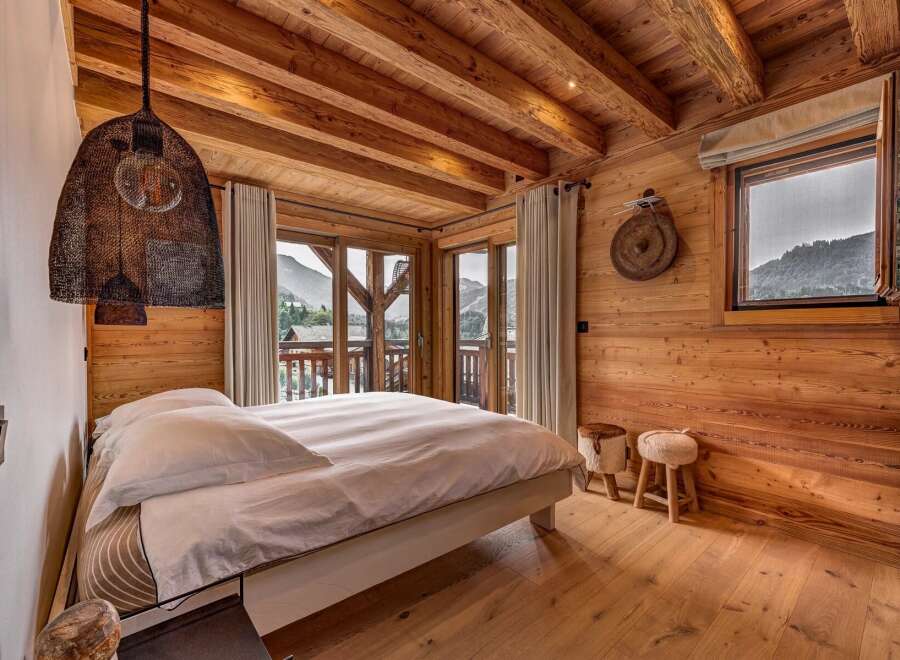 Experience rustic luxury in this charming mountain bedroom, featuring exposed wooden beams and walls that exude warmth.