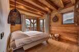 Experience rustic luxury in this charming mountain bedroom, featuring exposed wooden beams and walls that exude warmth.