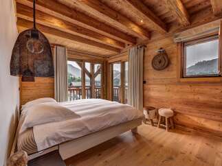 Experience rustic luxury in this charming mountain bedroom, featuring exposed wooden beams and walls that exude warmth.