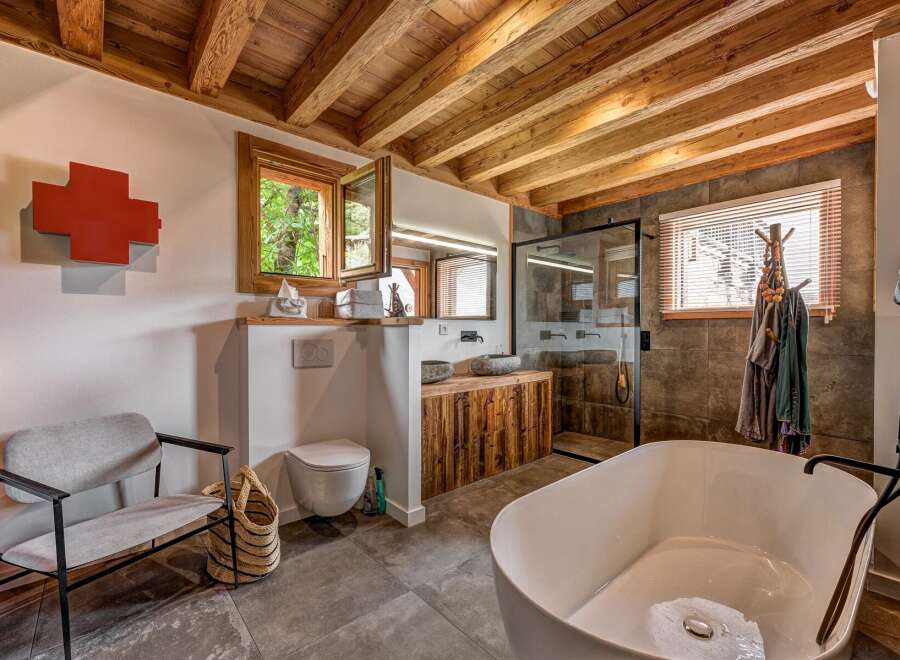 Experience rustic luxury in this stunning bathroom featuring a freestanding soaking tub and a walk-in shower with stone tile accents.