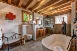Experience rustic luxury in this stunning bathroom featuring a freestanding soaking tub and a walk-in shower with stone tile accents.