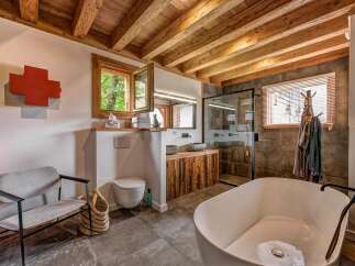 Experience rustic luxury in this stunning bathroom featuring a freestanding soaking tub and a walk-in shower with stone tile accents.