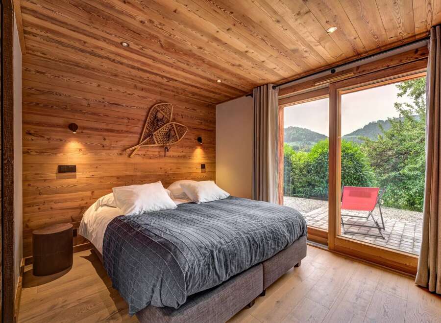 Experience rustic charm and modern comfort in this beautifully appointed bedroom, featuring warm wood paneling and a cozy king-sized bed.