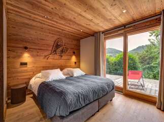 Experience rustic charm and modern comfort in this beautifully appointed bedroom, featuring warm wood paneling and a cozy king-sized bed.
