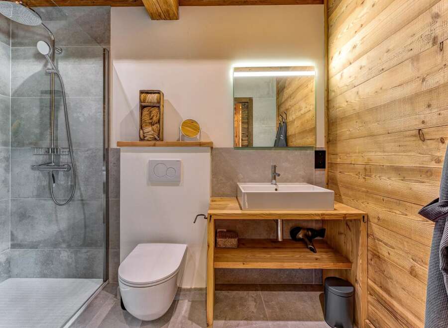 Experience rustic charm in this modern bathroom, featuring a spacious walk-in shower with grey tile accents and a sleek chrome shower system.