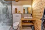 Experience rustic charm in this modern bathroom, featuring a spacious walk-in shower with grey tile accents and a sleek chrome shower system.