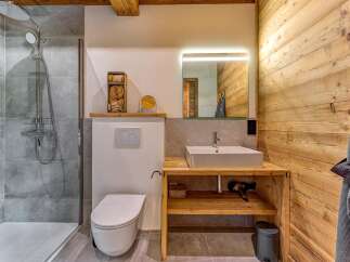 Experience rustic charm in this modern bathroom, featuring a spacious walk-in shower with grey tile accents and a sleek chrome shower system.