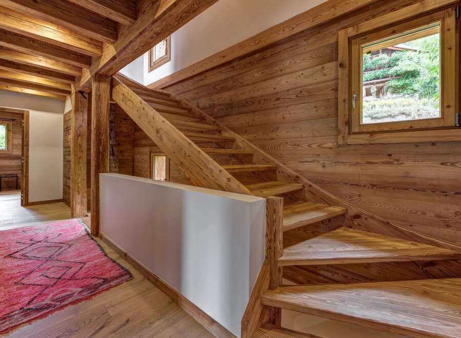 Experience rustic charm in this mountain chalet featuring a stunning wooden staircase and exposed beams.