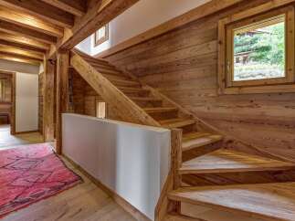 Experience rustic charm in this mountain chalet featuring a stunning wooden staircase and exposed beams.