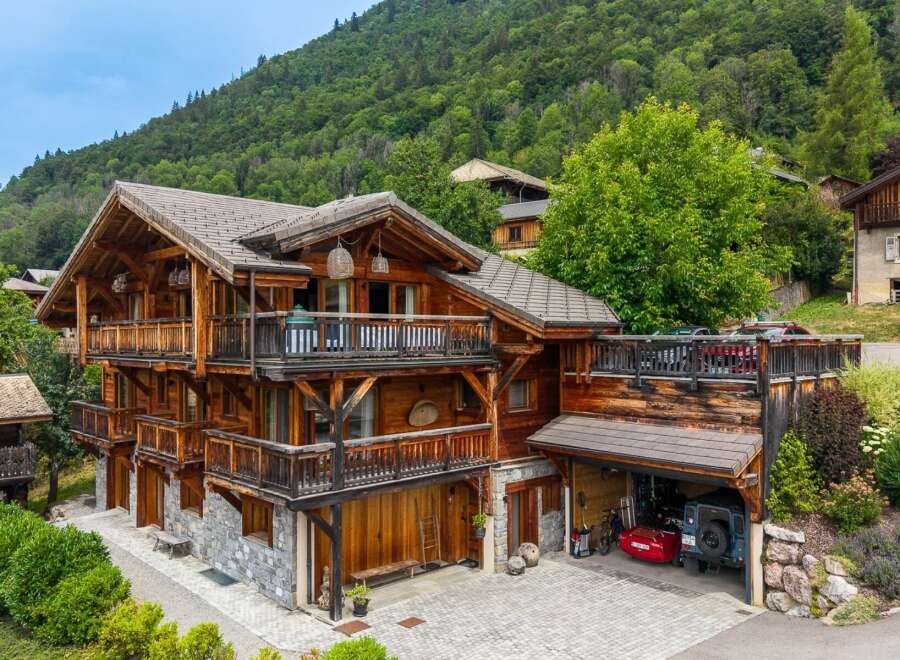 Experience luxury mountain living in this stunning wooden chalet, nestled against a lush green hillside.