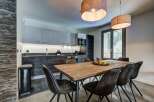 Experience modern living in this stylish dining area, featuring a rustic wooden table perfect for family gatherings.