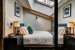 Experience cozy comfort in this charming bedroom, featuring a plush bed adorned with crisp white linens and a decorative blue throw pillow.