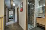 Discover this charming hallway featuring rustic wooden doors and a modern bathroom with a sleek shower and vanity.