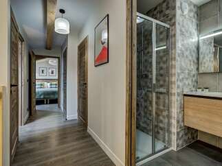 Discover this charming hallway featuring rustic wooden doors and a modern bathroom with a sleek shower and vanity.