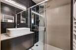Experience modern luxury in this stunning bathroom featuring a sleek vessel sink atop a dark vanity, complemented by a spacious glass-enclosed shower with a rainfall showerhead.