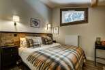 Experience cozy mountain living in this charming bedroom, featuring a rustic wooden headboard and a plush plaid blanket perfect for chilly evenings.