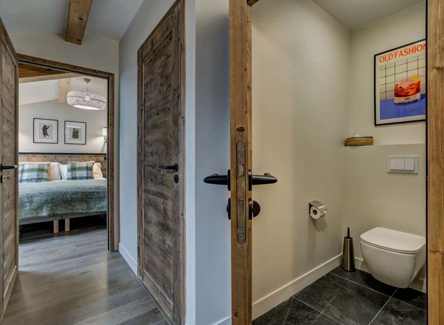 Step into a charming mountain retreat featuring rustic wooden doors and a cozy bedroom visible through an open doorway.