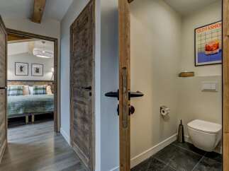 Step into a charming mountain retreat featuring rustic wooden doors and a cozy bedroom visible through an open doorway.