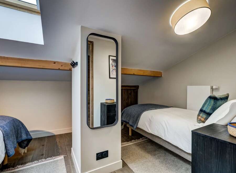 This charming attic bedroom features two cozy single beds, perfect for guests or a family.