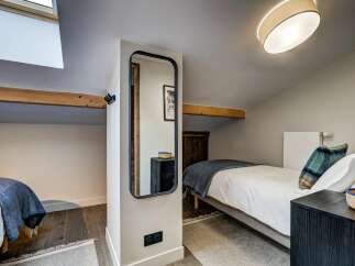 This charming attic bedroom features two cozy single beds, perfect for guests or a family.