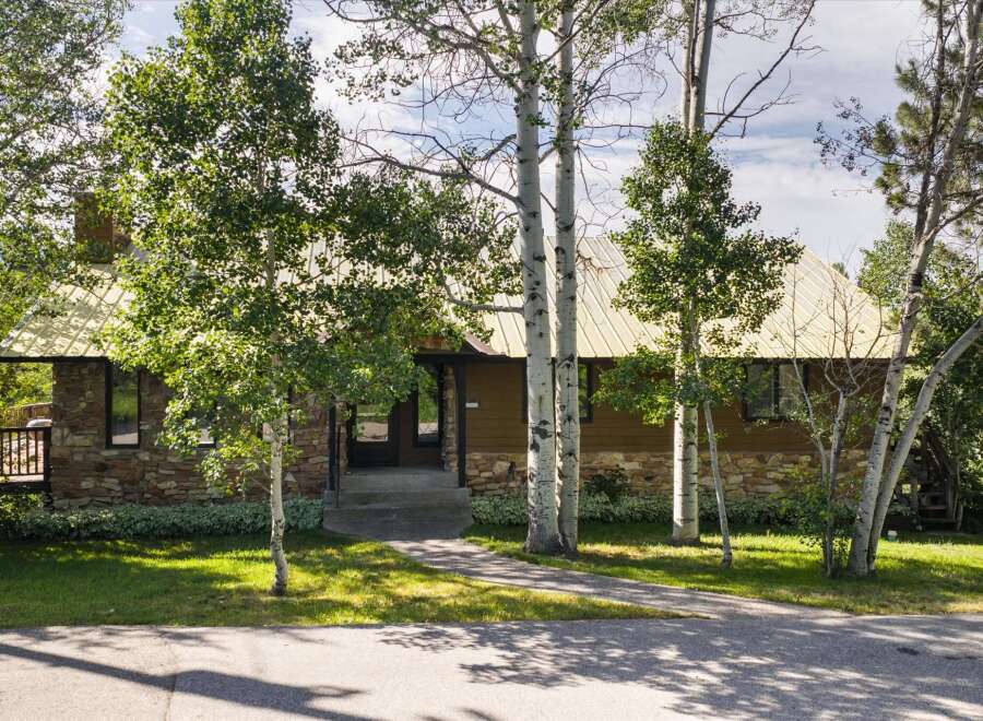 Nestled amongst mature trees, this charming home features a striking stone and wood exterior, complemented by a durable metal roof.